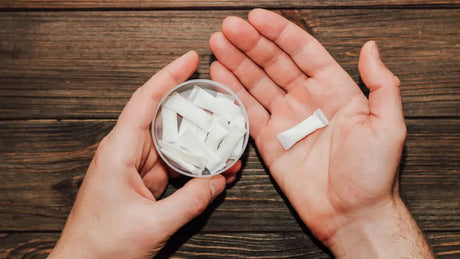 White nicotine pouches held in hand for a comparison of snus vs nicotine pouches